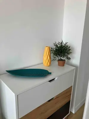 a white dresser with a plant and vases on it at Apartament Aleksandar Premium in Kyustendil