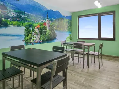 a dining room with tables and chairs and a painting on the wall at Хостел Стадиона in Pazardzhik