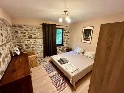 a bedroom with a bed in a room with a stone wall at Вила Динати in Perushtitsa