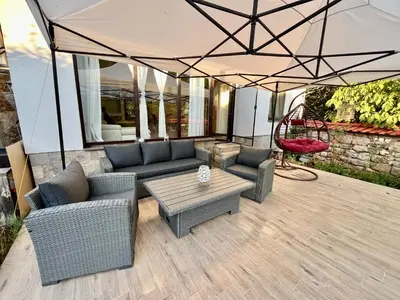 a patio with couches and a table and an umbrella at Вила Динати in Perushtitsa