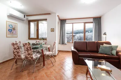 a living room with a couch and a table and chairs at Mountain View Apartment with Balcony & Ski Access nearby - Serendipity in Bansko