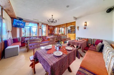 a restaurant with tables and chairs and a television at Hotel Mursal in Yagodina