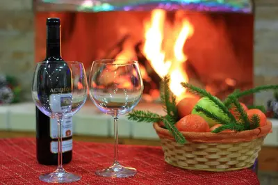 two wine glasses and a basket of fruit next to a fireplace at Hotel Mursal in Yagodina