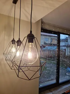 a cluster of lights hanging in a room with a window at Daisy Garden by the Church in Razlog