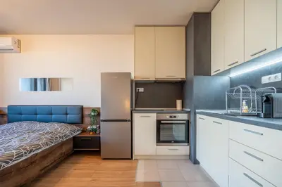 a kitchen with white cabinets and a bed in a room at Palitra Studio in Sofia