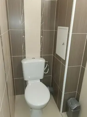 a bathroom with a white toilet and a trash can at Family Suite in Sofia