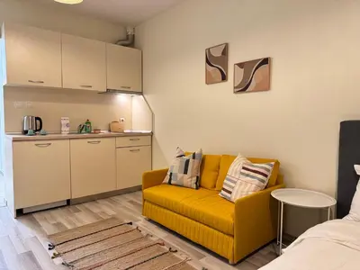 a living room with a yellow couch and a kitchen at Studio 108 by COSHER in Sofia