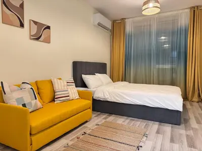 a living room with a yellow couch and a bed at Studio 108 by COSHER in Sofia