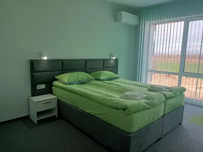 a bedroom with a large bed with green sheets and a window at Ubis Hotel in Krumovo