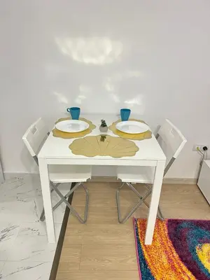 a white table with two plates and two chairs at Santorini modern and cosy Apt near UNSS and NSA w WiFi in Sofia