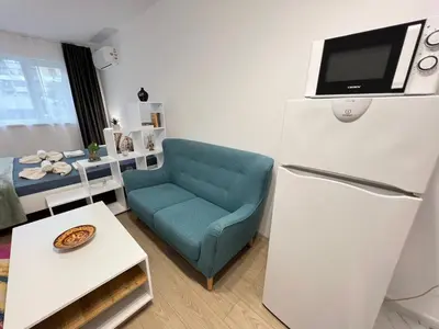 a living room with a blue chair and a refrigerator at Santorini modern and cosy Apt near UNSS and NSA w WiFi in Sofia