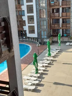 a row of lawn chairs with umbrellas next to a pool at Apartments Belvedere B303 in Bansko
