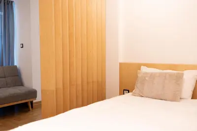 a bed with a wooden headboard next to a chair at Luxury studio 12-4 in Plovdiv