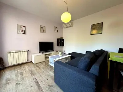 a living room with a blue couch and a tv at Cozy flat in central Sofia in Sofia