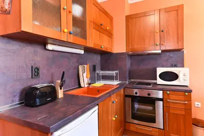 a kitchen with wooden cabinets and a sink and a microwave at Cedar Lodge III - One BDRM Flat B18 in Bansko