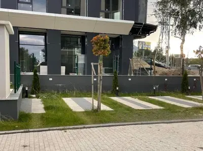 a tree in the grass in front of a building at Via421 by COSHER in Sofia