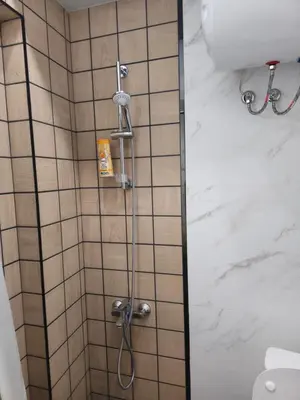 a shower in a bathroom with white tiles at New Premium COZY apartment in the center next to NDK in Sofia
