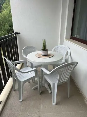 a white table and chairs on a balcony with a potted plant at large apartment in Borovets in Borovets