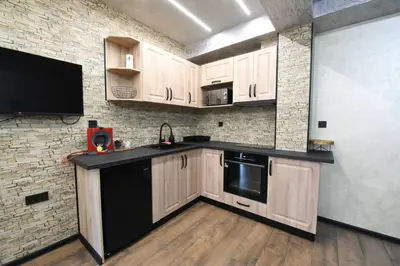 a kitchen with wooden cabinets and a black appliance at Студио Анастасия in Smolyan