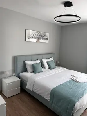 a white bedroom with a large bed with blue pillows at Apartmenthaus Oborishte 2-3-10 in Panagyurishte