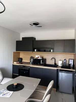 a kitchen with black cabinets and a table and a sink at Apartmenthaus Oborishte 2-3-10 in Panagyurishte