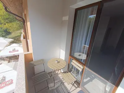 a balcony with a table and a glass door at Комплекс Кантона in Razhishte