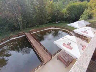 a pool of water with two tables and umbrellas at Комплекс Кантона in Razhishte