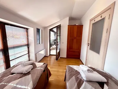 two beds in a room with a hallway with windows at Bansko&Ski in Bansko