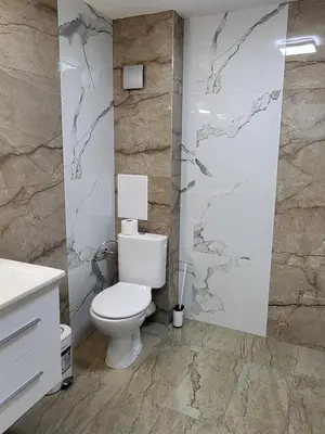 a bathroom with a toilet and a stone wall at Панорамен Пентхаус - Кабинков лифт - 3 спални in Bansko