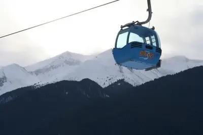 a gondola flying over a snow covered mountain at Панорамен Пентхаус - Кабинков лифт - 3 спални in Bansko