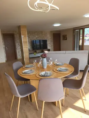 a dining room with a wooden table and chairs at Панорамен Пентхаус - Кабинков лифт - 3 спални in Bansko
