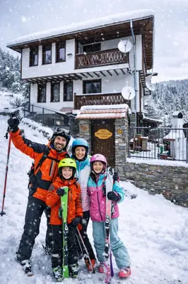 a family posing for a picture in the snow at Nachovata Guest House Stoykite, near Pamporovo in Vodata