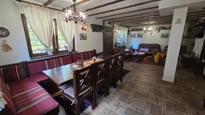 a dining room and living room with a table and chairs at Nachovata Guest House Stoykite, near Pamporovo in Vodata