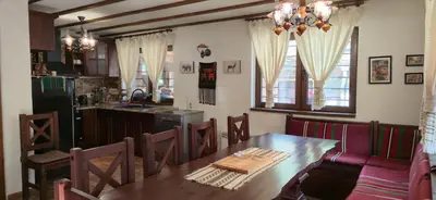 a dining room with a table and a kitchen at Nachovata Guest House Stoykite, near Pamporovo in Vodata