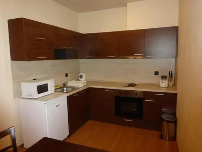 a small kitchen with wooden cabinets and a microwave at Two-Bedroom Apartment in Fortuna in Bansko