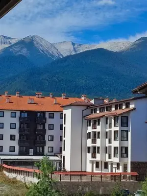 a large white building with mountains in the background at Dream 1BRoom Private Apartment in Bansko