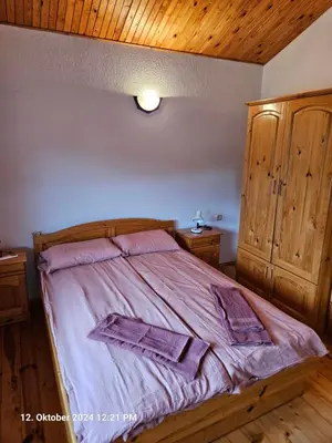 a bedroom with a bed with purple sheets and wooden ceilings at Villa Dilyanka Stokite in Stoykite