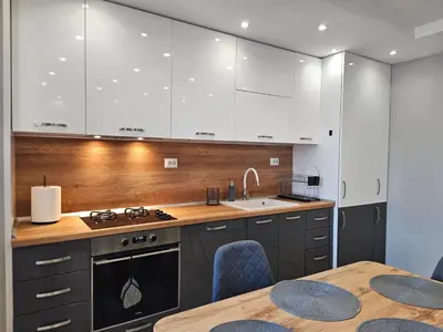 a kitchen with white cabinets and a table with chairs at Boutique apartment yellow 1 in Plovdiv