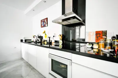 a kitchen with white cabinets and a black counter top at 1BDR Quiet Str Vitoshka Area AC in Sofia