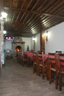 a dining room with a table and chairs and a fireplace at Leshtenski Perli in Leshten