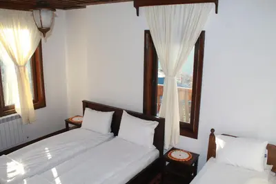 a bedroom with two beds and two windows at Leshtenski Perli in Leshten