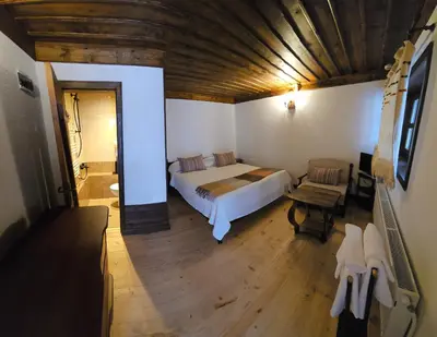 a bedroom with a large bed and a wooden ceiling at Къща за гости Имало едно време in Smolyan