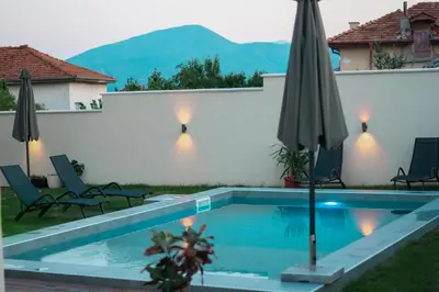 a swimming pool with two chairs and an umbrella at Самуил къща за гости in Ognyanovo