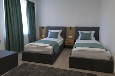 two beds in a room with green curtains at Самуил къща за гости in Ognyanovo