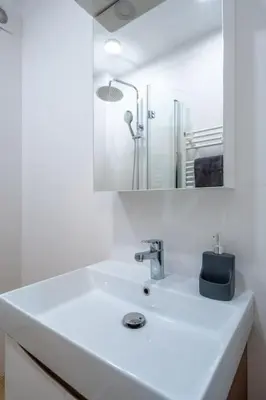 a white bathroom with a sink and a mirror at Modern and Calm 2BDRM Apt in City Centre in Sofia