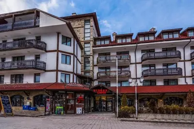 a large white building with balconies on a street at Friendly apartment -top location in Bansko