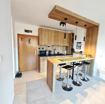 a kitchen with wooden cabinets and a island with bar stools at Friendly apartment -top location in Bansko