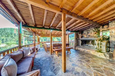 an outdoor dining room with a stone fireplace at Valkanovi House in Pamporovo