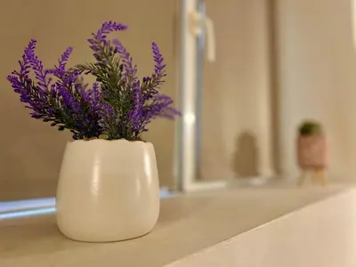 a white vase with purple flowers in it on a counter at TOP Center, basement fl, 7 beds, 10min from Serdica in Sofia