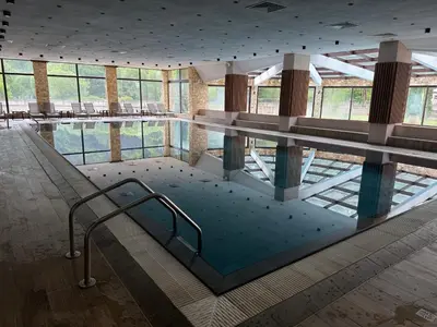 a swimming pool in a large building with chairs and tables at Мия4 Спа хотел Свети Спас in Velingrad